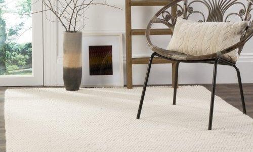 Cozy minimalist room with a white rug, a chair, ladder, and decorative vases.